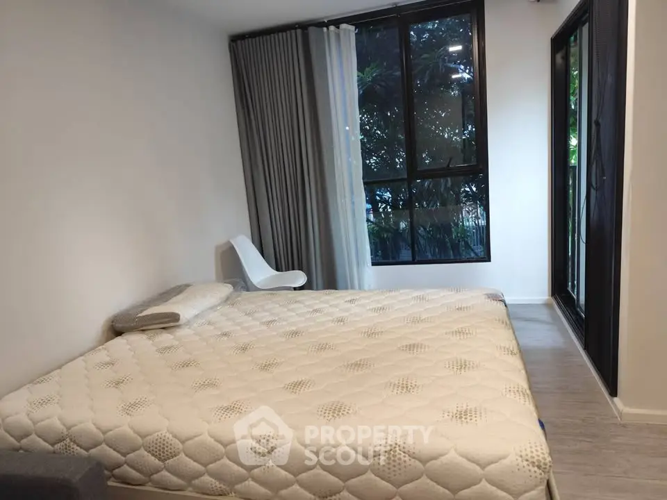 Modern bedroom with large window and garden view, featuring minimalist decor and comfortable bed.