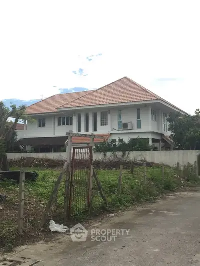 Charming two-story house with a red-tiled roof and spacious yard, perfect for family living.