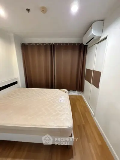 Cozy bedroom with wooden flooring and air conditioning, featuring a comfortable bed and ample closet space.