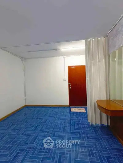 Spacious room with vibrant blue flooring and wooden door, ideal for creative interior design.