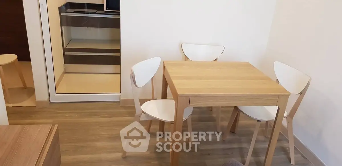 Modern dining area with wooden table and chairs in a cozy apartment setting.