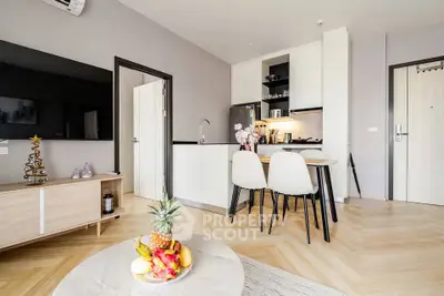 Modern open-plan living room with stylish kitchen and dining area, featuring sleek furniture and elegant decor.