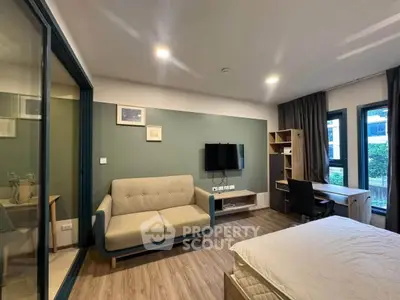 Modern bedroom with stylish decor, featuring a cozy sofa, wall-mounted TV, and a functional study area.