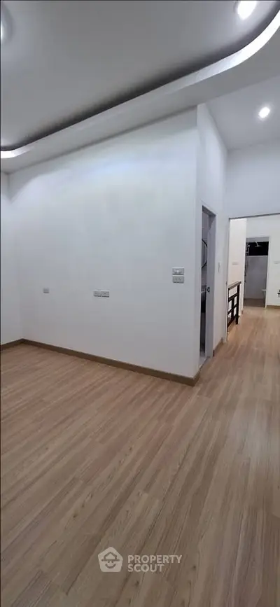 Spacious modern living room with sleek wooden flooring and recessed lighting.