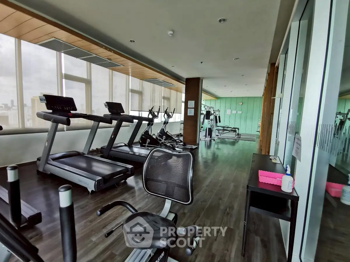 Spacious modern gym with state-of-the-art equipment and large windows for natural light.