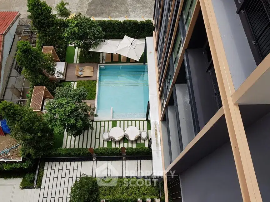 Stunning aerial view of modern apartment complex with pool and lush greenery.