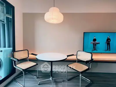 Modern living room with stylish chairs, round table, and wall-mounted TV, perfect for contemporary living.