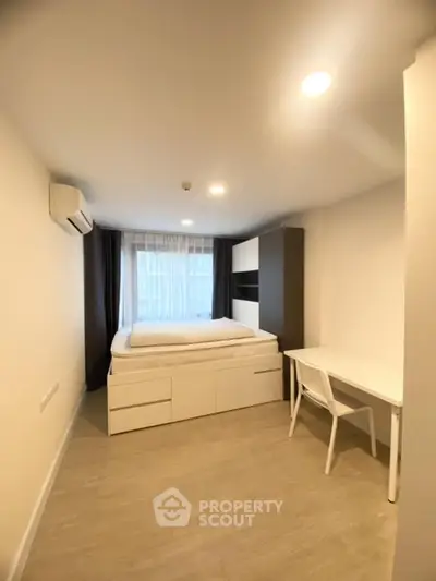 Modern bedroom with minimalist design, featuring a bed with storage, desk, and large window for natural light.
