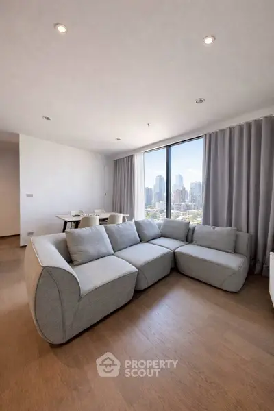 Spacious modern living room with city view and stylish gray sectional sofa.