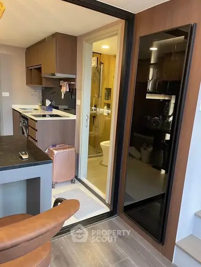 Modern compact kitchen with open layout and sleek design, adjacent to a stylish bathroom.