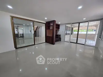 Spacious living room with large windows and glossy tiled floors in modern home.