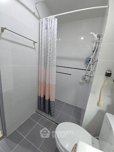 Modern bathroom with shower curtain and tiled floor in a contemporary home.