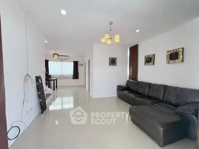 Spacious modern living room with sleek black leather sofa and elegant lighting, perfect for relaxation and entertainment.