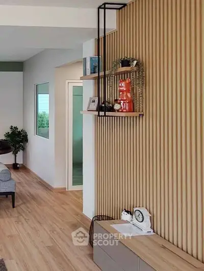 Modern living room with stylish wooden panel wall and decorative shelves.