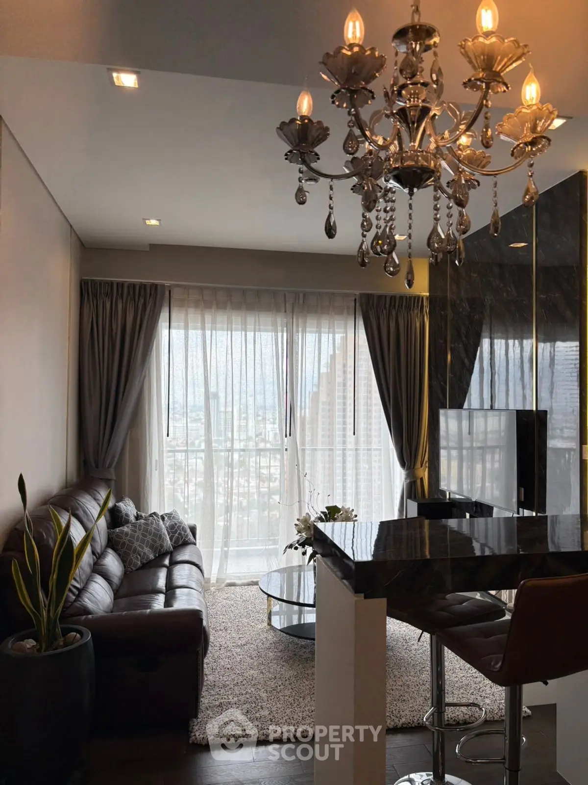 Luxurious living room with chandelier and city view, featuring modern decor and elegant furnishings.
