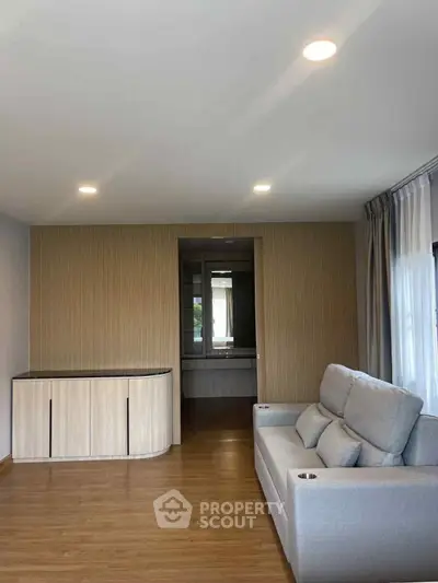 Modern living room with sleek wooden flooring and cozy gray sofa, perfect for relaxation and entertainment.