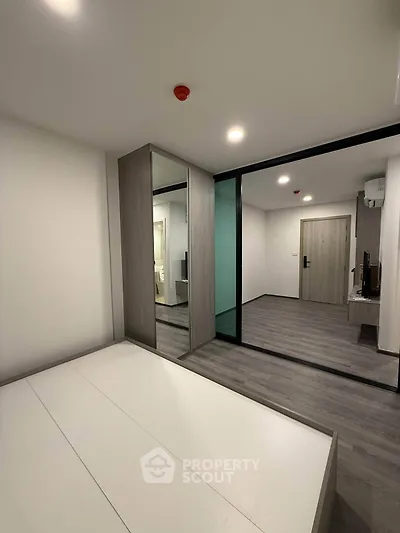 Modern minimalist bedroom with mirrored wardrobe and sleek flooring