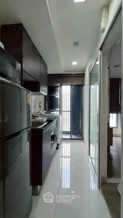 Modern kitchen with sleek dark cabinets and stainless steel appliances in a stylish apartment.