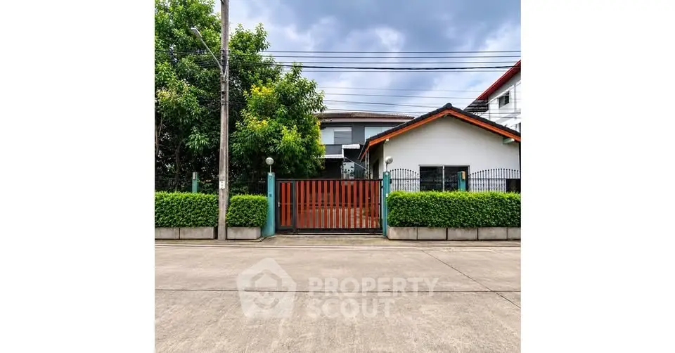 Charming suburban house with lush greenery and secure gated entrance.