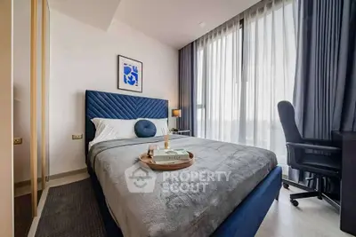 Modern bedroom with stylish decor and large window offering natural light.