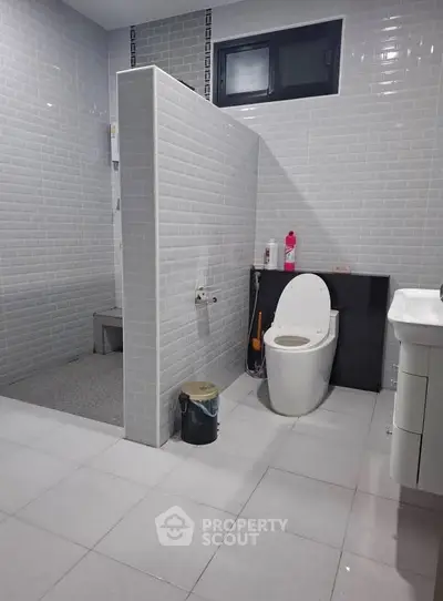 Modern bathroom with sleek design and tiled walls, featuring a toilet and shower area.
