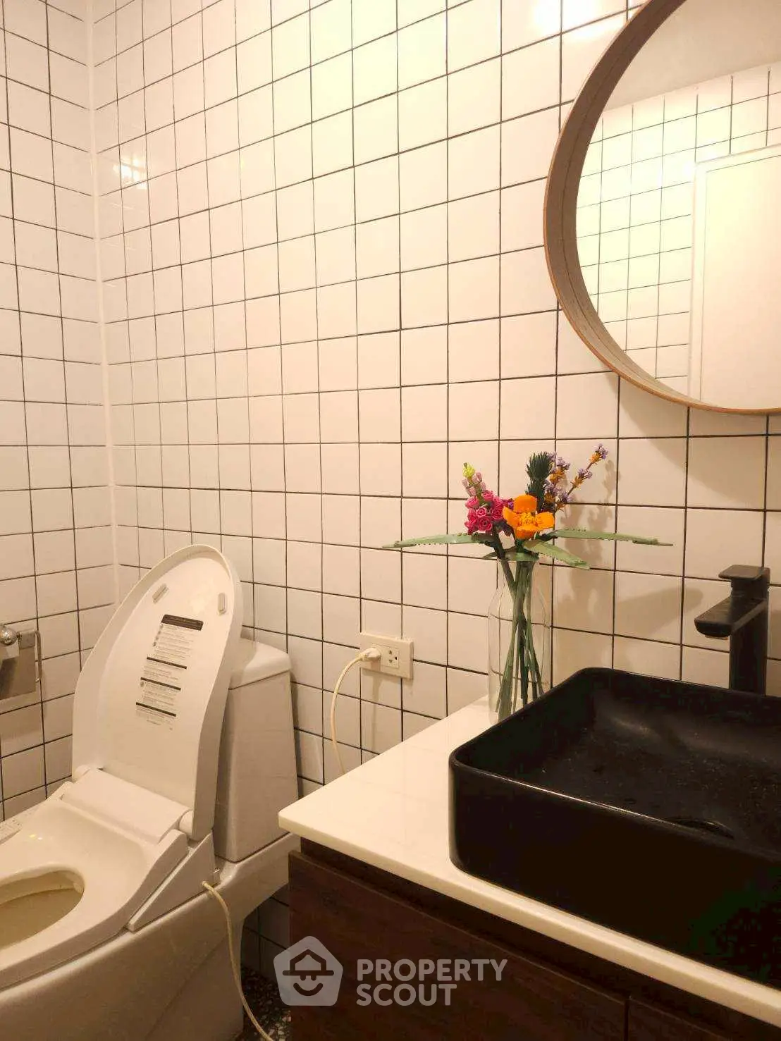 Modern bathroom with stylish black sink and round mirror