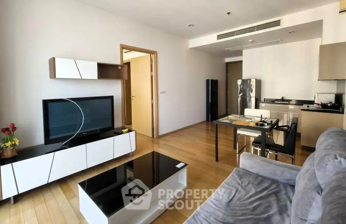 Modern living room with open kitchen, sleek furniture, and wooden flooring in a stylish apartment.