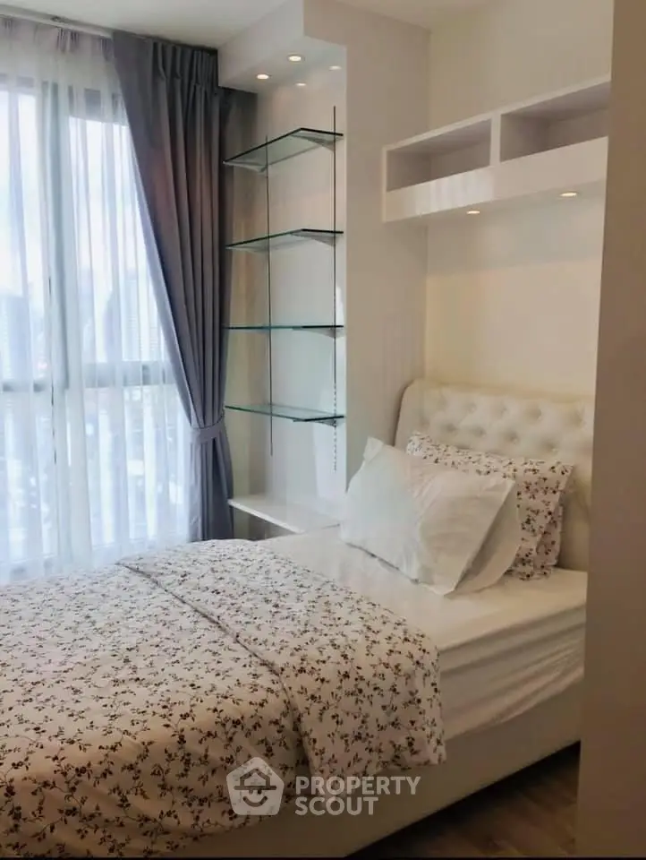 Cozy bedroom with modern decor and large window offering natural light.
