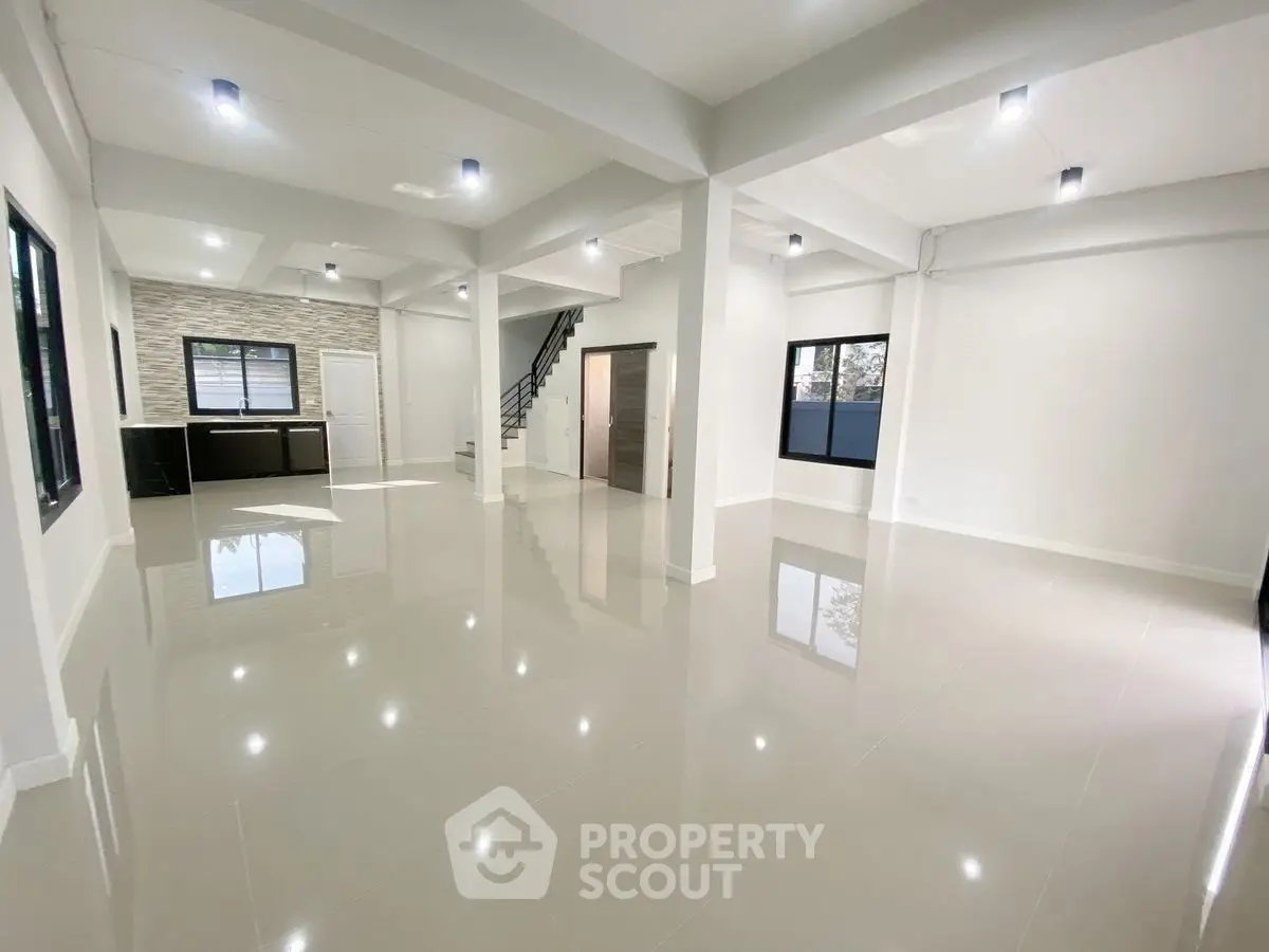 Spacious open-plan living area with modern kitchen and sleek tile flooring.