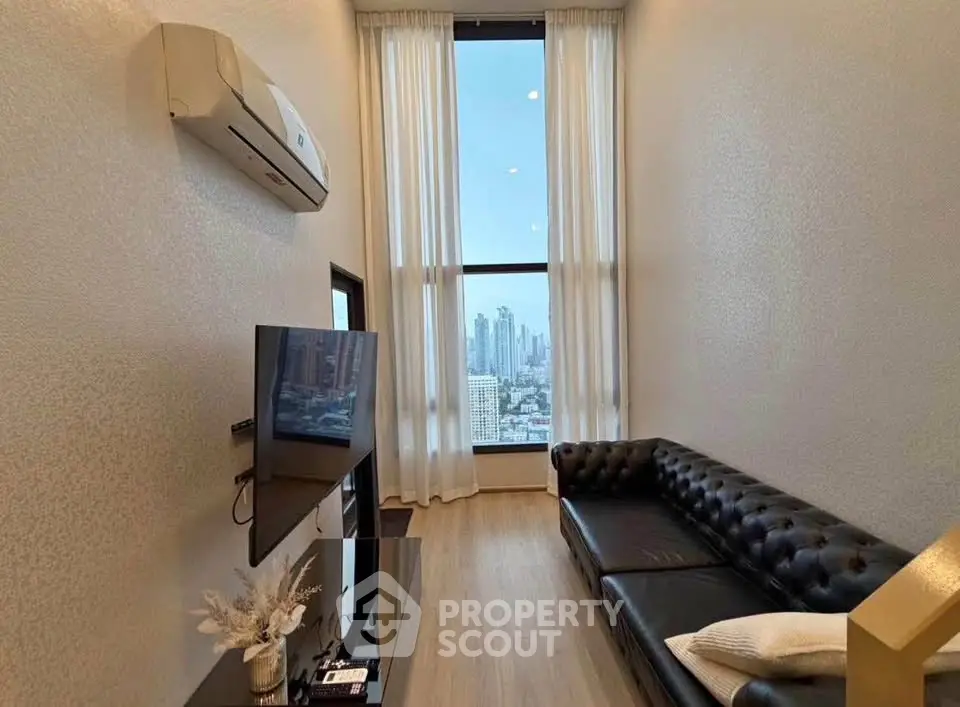 Modern living room with city view, featuring sleek black leather sofa and wall-mounted TV.