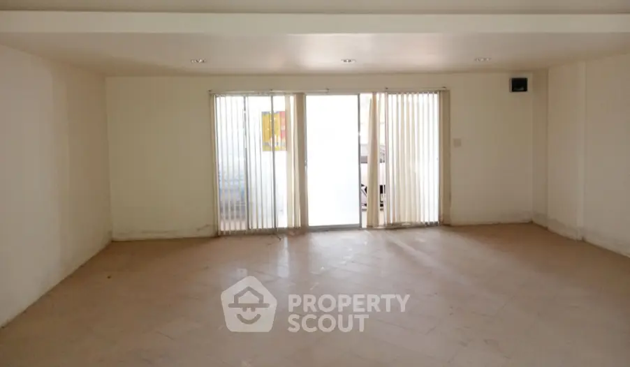 Spacious empty room with tiled floor and sliding glass doors leading to balcony.