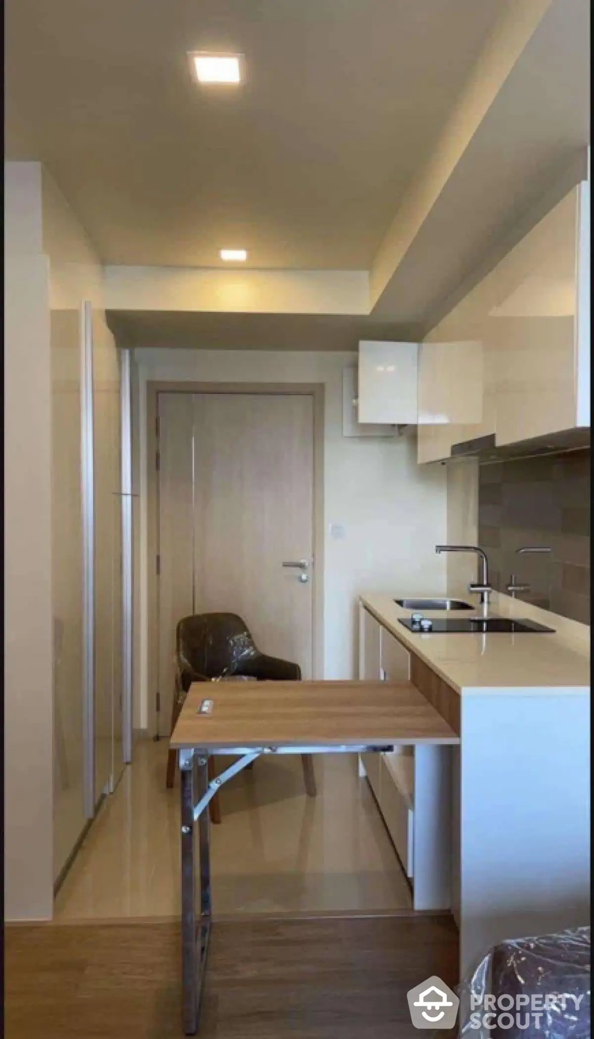 Modern compact kitchen with sleek cabinetry and folding table in stylish apartment.