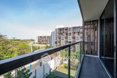 Modern balcony with glass railing overlooking contemporary apartment complex