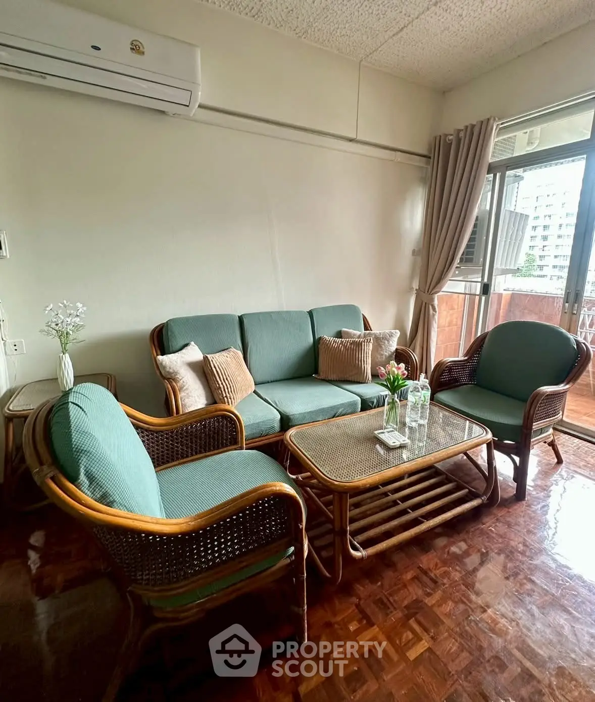 Cozy living room with rattan furniture and balcony view, perfect for relaxation.