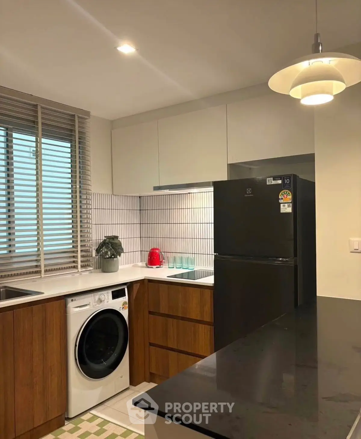 Modern kitchen with sleek appliances and stylish cabinetry, featuring a washing machine and elegant lighting.