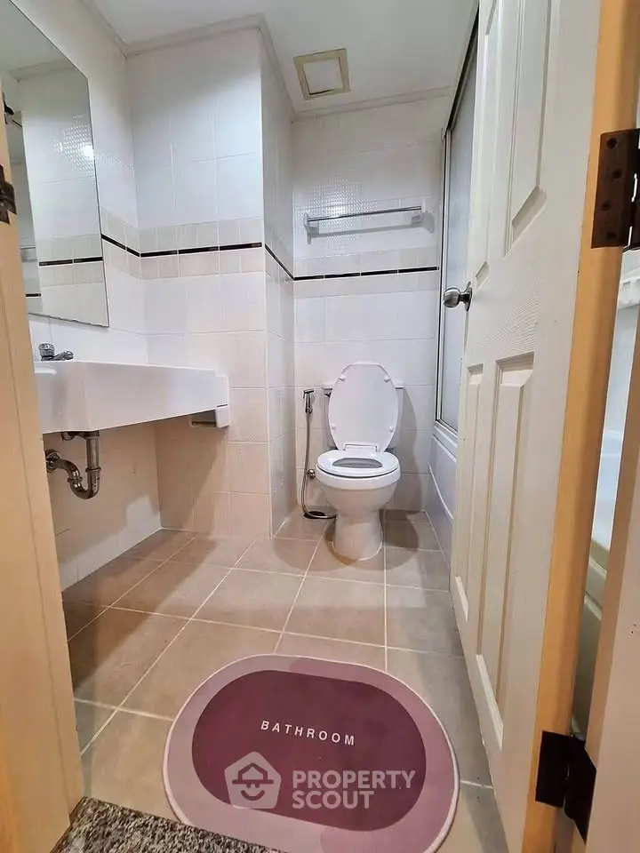 Modern bathroom with sleek fixtures and neutral tiles, featuring a toilet and sink.