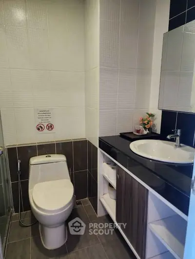 Modern bathroom with sleek design, featuring a toilet, sink, and glass shower enclosure.