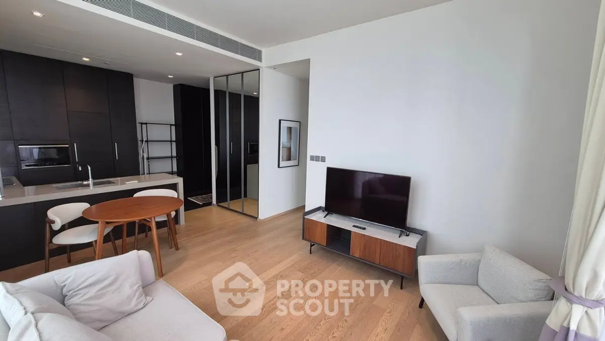 Modern living room with open kitchen, sleek furniture, and natural light