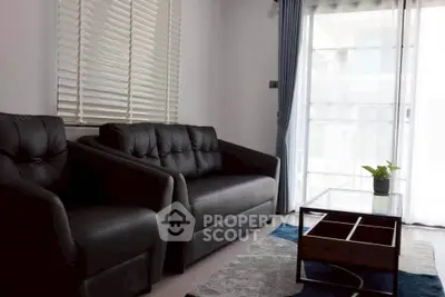Modern living room with sleek black sofas and natural light.