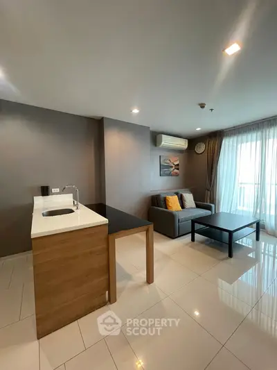 Modern living room with open kitchen, sleek furniture, and large windows for natural light.