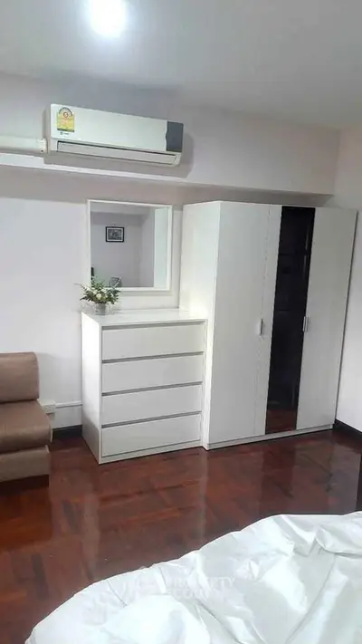 Spacious bedroom with modern white furniture and air conditioning unit.