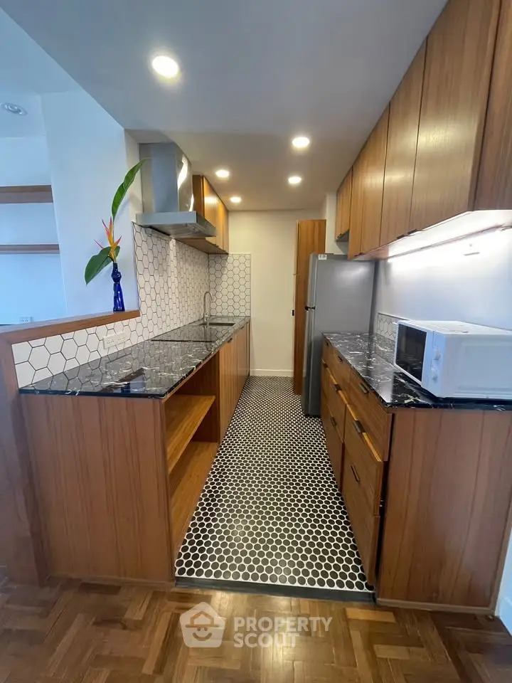 Modern kitchen with sleek wooden cabinets and stylish hexagonal tile flooring.