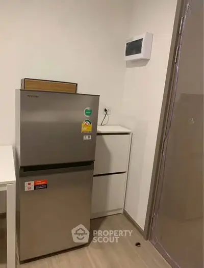 Modern kitchen corner with sleek fridge and minimalist design, perfect for compact living spaces.