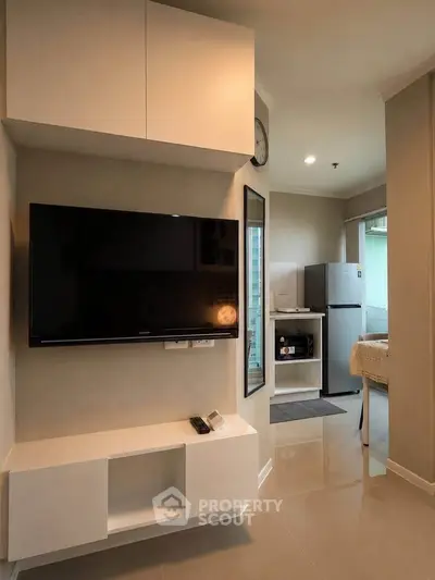 Modern living room with sleek TV setup and open kitchen view in stylish apartment.