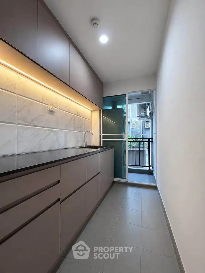 Modern kitchen with sleek cabinetry and balcony access in urban apartment