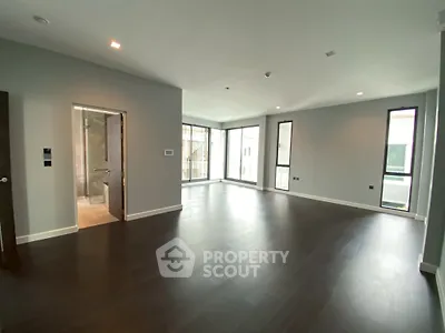 Spacious modern living room with dark wood flooring and large windows