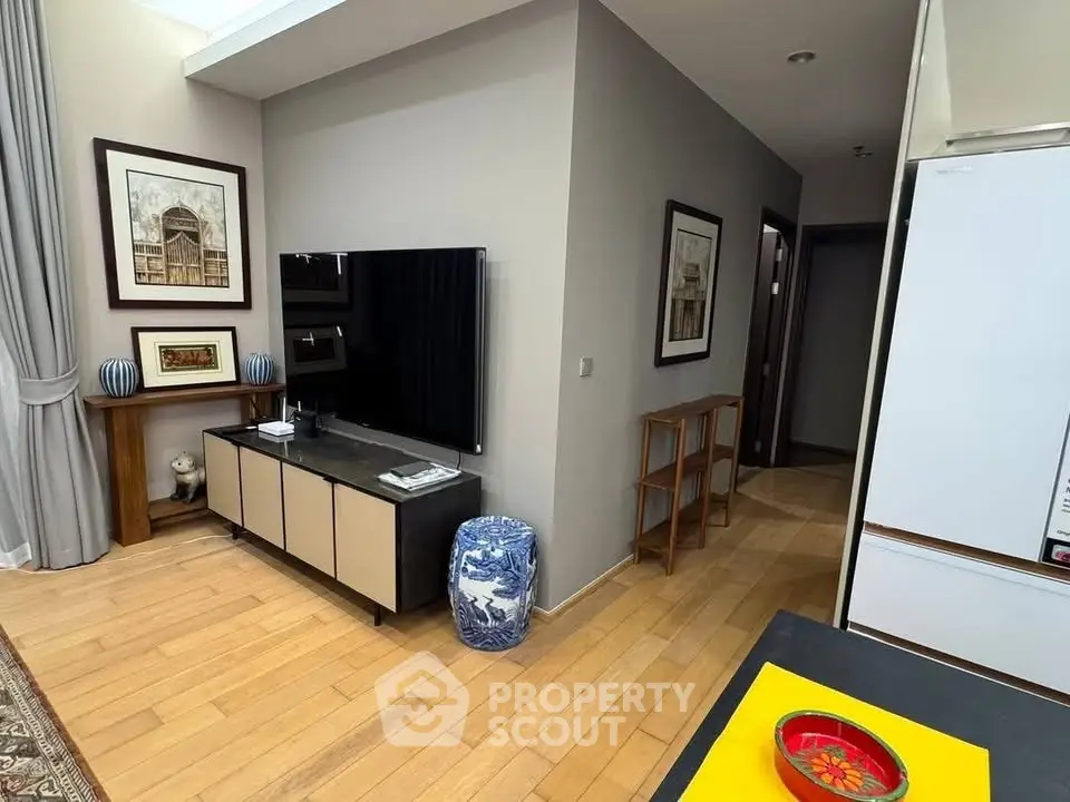 Stylish living room with modern decor and wooden flooring, featuring a sleek TV setup and elegant artwork.