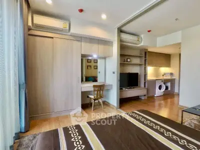 Modern bedroom with sliding doors, built-in wardrobe, and in-unit washer in open layout apartment.