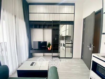 Modern living room with sleek storage, TV, and balcony view in stylish apartment.
