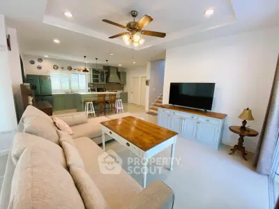 Spacious open-plan living room with modern kitchen and cozy seating area, perfect for family gatherings.